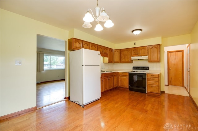 8866 Meadowlark Dr, Franklin, OH 45005 - kitchen featuring freestanding refrigerator, range with electric stovetop, under cabinet range hood, a chandelier, and light countertops