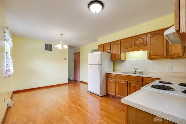 8866 Meadowlark Dr, Franklin, OH 45005 - kitchen featuring freestanding refrigerator, under cabinet range hood, a chandelier, and brown cabinets