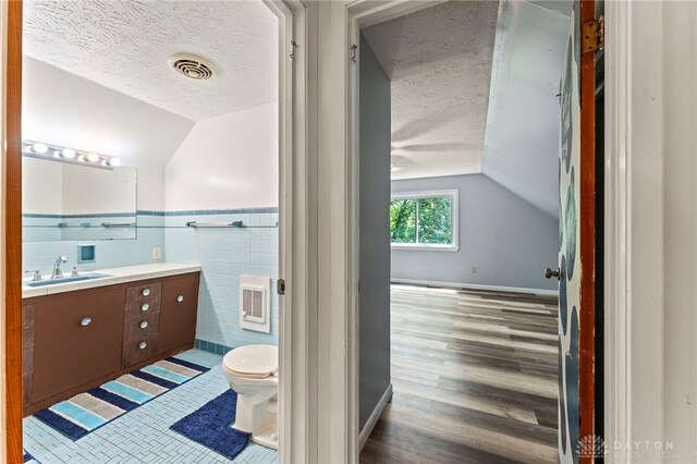 405 Hyde Park Dr, Hamilton, OH 45013 - bathroom featuring vanity, tile walls, a textured ceiling, vaulted ceiling, and wood finished floors
