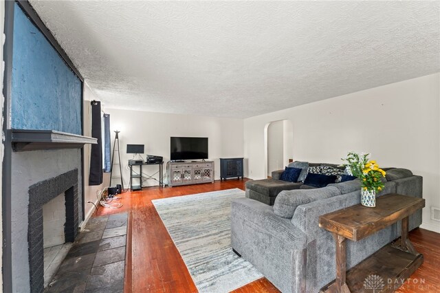 405 Hyde Park Dr, Hamilton, OH 45013 - living room with a large fireplace, dark wood finished floors, arched walkways, and a textured ceiling