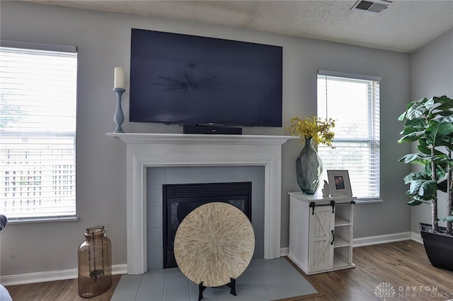 11 Green Meadow Ct, Franklin, OH 45005 - detailed view of wood finished floors, a tiled fireplace, and a textured ceiling