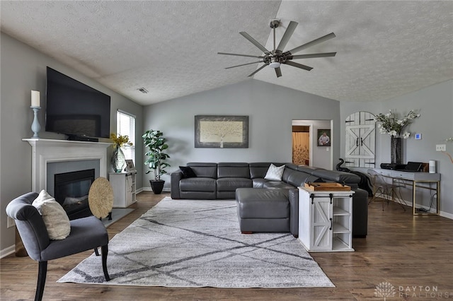 11 Green Meadow Ct, Franklin, OH 45005 - living room with a textured ceiling, a ceiling fan, vaulted ceiling, a glass covered fireplace, and wood finished floors
