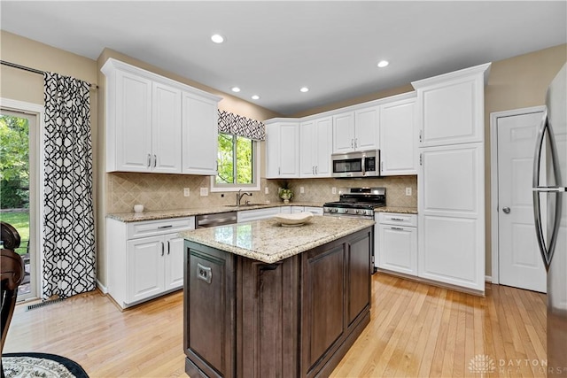 1027 W Bridlepath Ln, Miami Twp, OH 45140 - kitchen featuring appliances with stainless steel finishes, light wood finished floors, plenty of natural light, white cabinetry, and recessed lighting