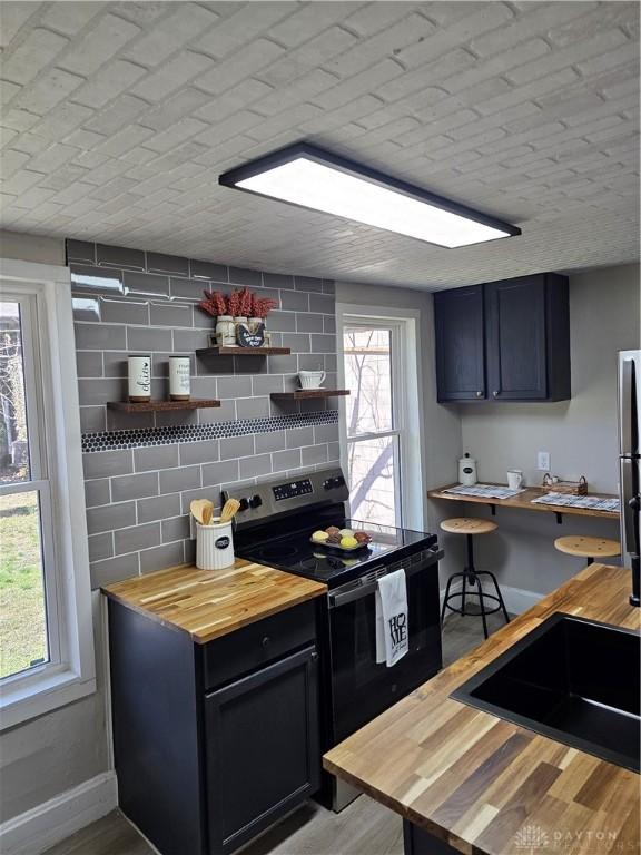 904 Crawford St, Middletown, OH 45044 - kitchen featuring wood counters, stainless steel electric range, open shelves, tasteful backsplash, and a breakfast bar