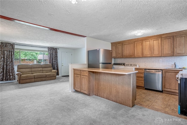 4501 Hannaford St, Miami Twp, OH 45439 - kitchen featuring stainless steel appliances, light colored carpet, brown cabinets, open floor plan, and light countertops