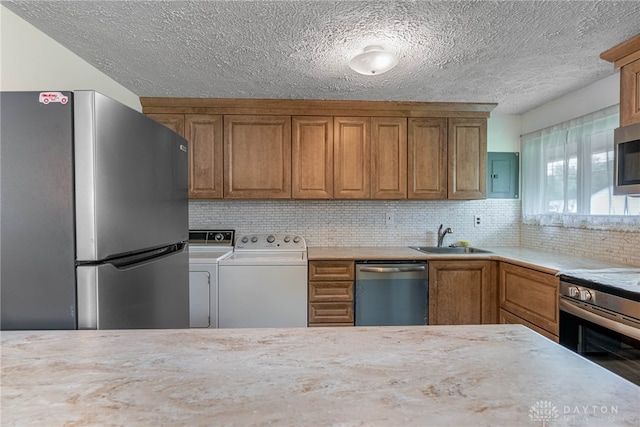 4501 Hannaford St, Miami Twp, OH 45439 - kitchen with appliances with stainless steel finishes, washer and clothes dryer, brown cabinets, light countertops, and a textured ceiling
