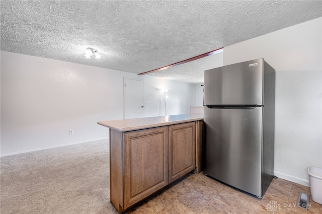 4501 Hannaford St, Miami Twp, OH 45439 - kitchen with freestanding refrigerator, a peninsula, brown cabinetry, light countertops, and a textured ceiling