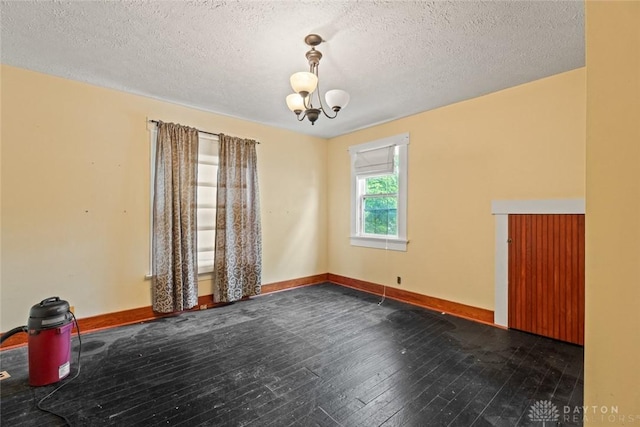 2311 S Dixie Dr, Kettering, OH 45409 - empty room with dark wood-type flooring, a textured ceiling, and a chandelier