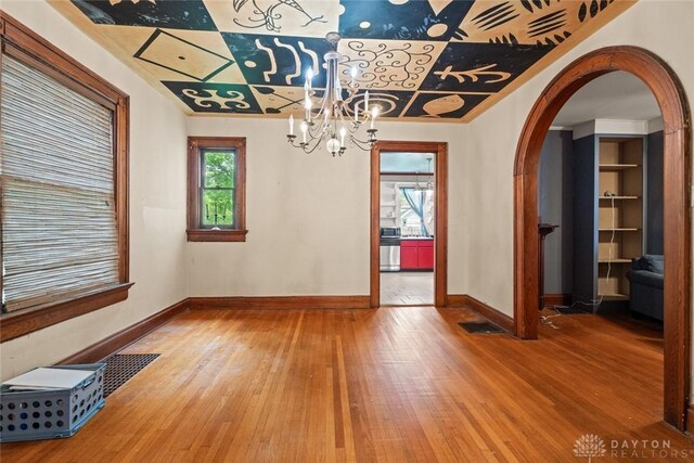 2311 S Dixie Dr, Kettering, OH 45409 - unfurnished dining area with wood-type flooring, arched walkways, and a chandelier