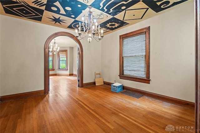 2311 S Dixie Dr, Kettering, OH 45409 - unfurnished dining area with a chandelier, arched walkways, and hardwood / wood-style flooring