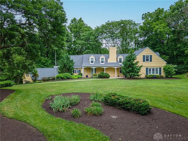1919 Tait Circle Rd, Kettering, OH 45429 - cape cod-style house with a chimney, a front yard, covered porch, and view of scattered trees