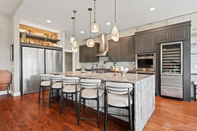 79 White Beech Ct, Springboro, OH 45066 - kitchen featuring stainless steel appliances, wall chimney exhaust hood, light stone countertops, dark wood-type flooring, and recessed lighting
