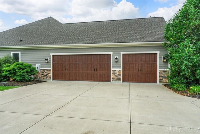79 White Beech Ct, Springboro, OH 45066 - view of home's exterior featuring stone siding, driveway, an attached garage, and roof with shingles