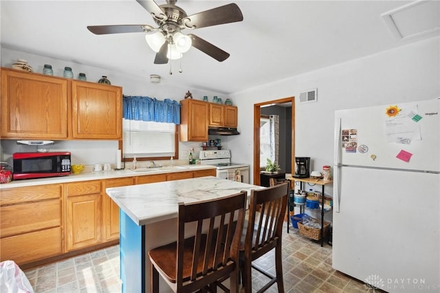 313 N High St, Wilmington, OH 45177 - kitchen featuring white appliances, light countertops, under cabinet range hood, a breakfast bar area, and a ceiling fan