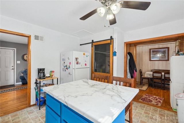 313 N High St, Wilmington, OH 45177 - kitchen with freestanding refrigerator, blue cabinetry, ceiling fan, and a kitchen island