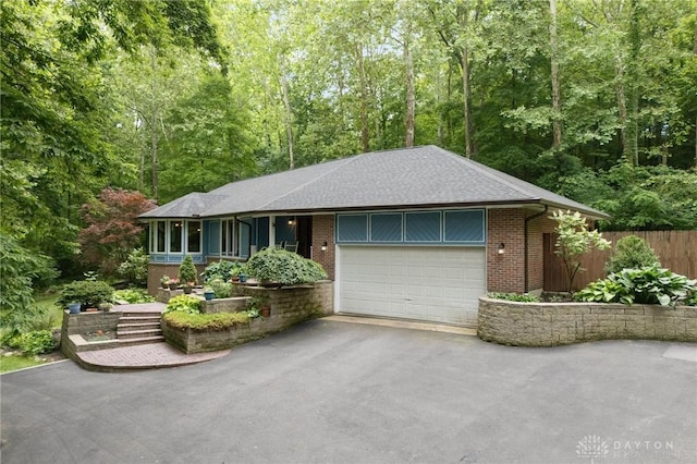 923 Lewis Creek Ct, Xenia, OH 45385 - ranch-style house with driveway, brick siding, a garage, and a forest view