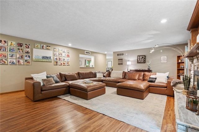 923 Lewis Creek Ct, Xenia, OH 45385 - living room featuring wood finished floors, a stone fireplace, a textured ceiling, and recessed lighting