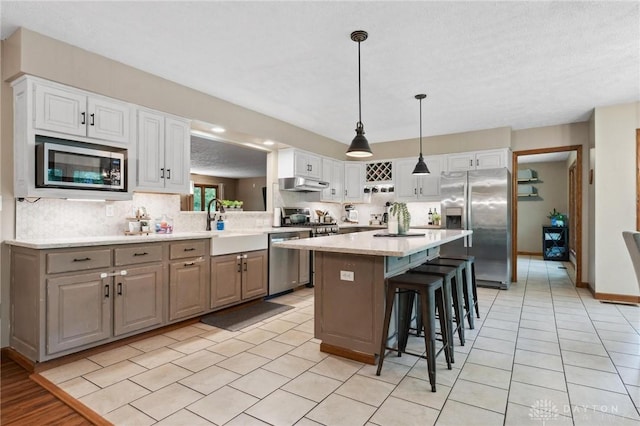 923 Lewis Creek Ct, Xenia, OH 45385 - kitchen with appliances with stainless steel finishes, a kitchen island, a kitchen bar, light countertops, and white cabinetry