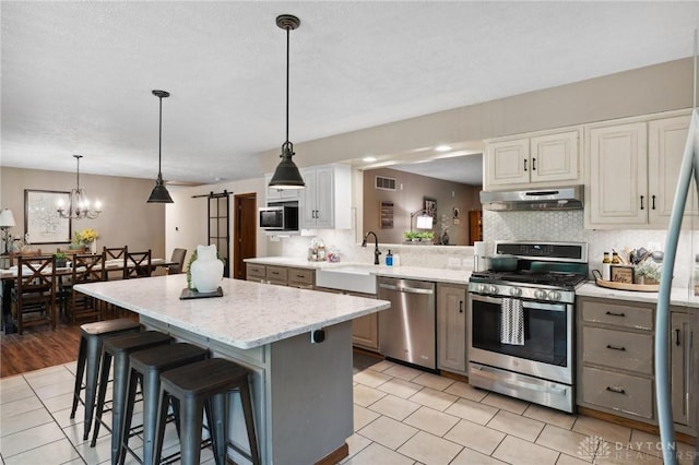 923 Lewis Creek Ct, Xenia, OH 45385 - kitchen with stainless steel appliances, under cabinet range hood, a center island, decorative backsplash, and light tile patterned floors