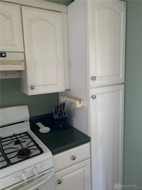 2222 Koebel Rd, Columbus, OH 43207 - kitchen featuring white range with gas cooktop, custom exhaust hood, dark countertops, and white cabinetry