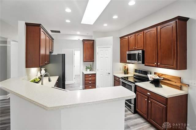 10101 Sawtry Ln, Washington Twp, OH 45458 - kitchen with appliances with stainless steel finishes, a peninsula, light wood finished floors, recessed lighting, and light countertops