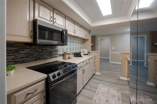 521 Park Ridge Dr, Centerville, OH 45459 - kitchen featuring black range with electric stovetop, ornamental molding, a tray ceiling, light countertops, and light wood finished floors