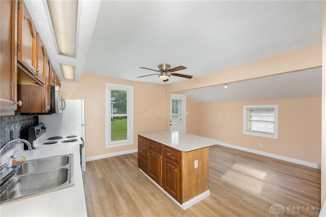824 Euclid St, Bellefontaine, OH 43311 - kitchen featuring stainless steel microwave, light wood-type flooring, brown cabinets, ceiling fan, and a center island