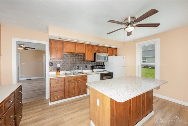824 Euclid St, Bellefontaine, OH 43311 - kitchen with white appliances, a ceiling fan, light wood-style floors, backsplash, and brown cabinetry
