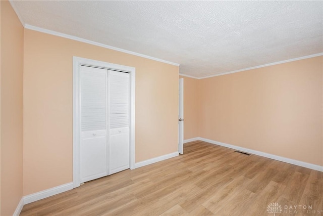 824 Euclid St, Bellefontaine, OH 43311 - unfurnished bedroom with light wood-style floors, crown molding, a textured ceiling, and a closet