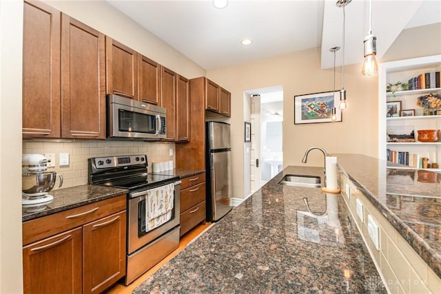 2356 Park Ave Unit 9, Cincinnati, OH 45206 - kitchen featuring appliances with stainless steel finishes, hanging light fixtures, brown cabinetry, dark stone countertops, and decorative backsplash