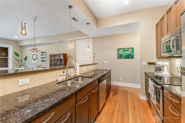 2356 Park Ave Unit 9, Cincinnati, OH 45206 - kitchen featuring stainless steel appliances, light wood finished floors, brown cabinets, backsplash, and recessed lighting