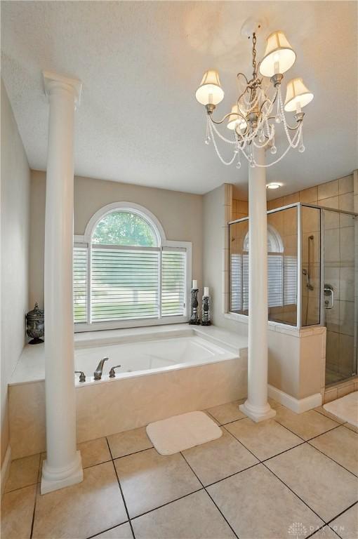 655 Devanshae Ct, Hamilton, OH 45013 - bathroom featuring decorative columns, a bath, a stall shower, tile patterned floors, and a chandelier