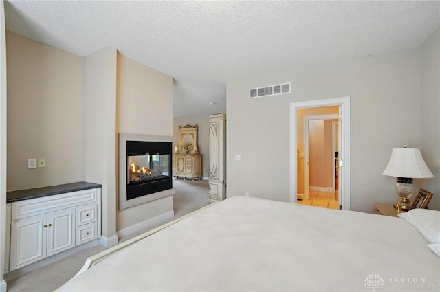 655 Devanshae Ct, Hamilton, OH 45013 - bedroom with light carpet, a multi sided fireplace, a textured ceiling, and connected bathroom