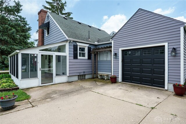 1603 Rosemont Blvd, Dayton, OH 45410 - rear view of house featuring a chimney, a sunroom, driveway, a shingled roof, and a garage
