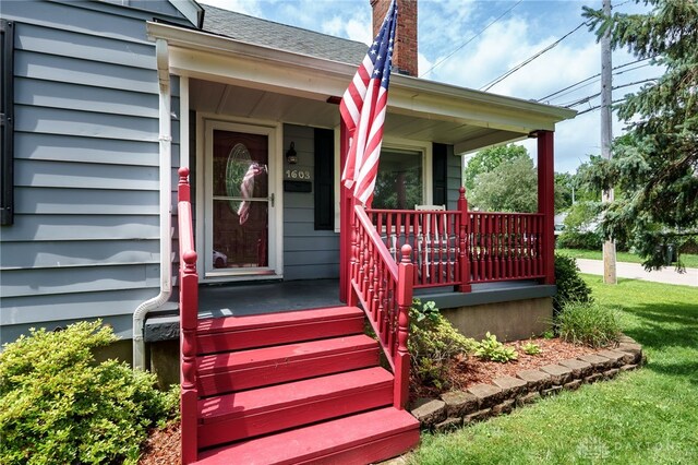1603 Rosemont Blvd, Dayton, OH 45410 - view of exterior entry featuring covered porch, a chimney, roof with shingles, and a yard