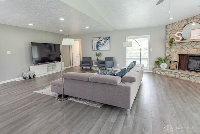 881 Garver Rd, Monroe, OH 45044 - living room featuring wood finished floors, a textured ceiling, a stone fireplace, ceiling fan, and recessed lighting