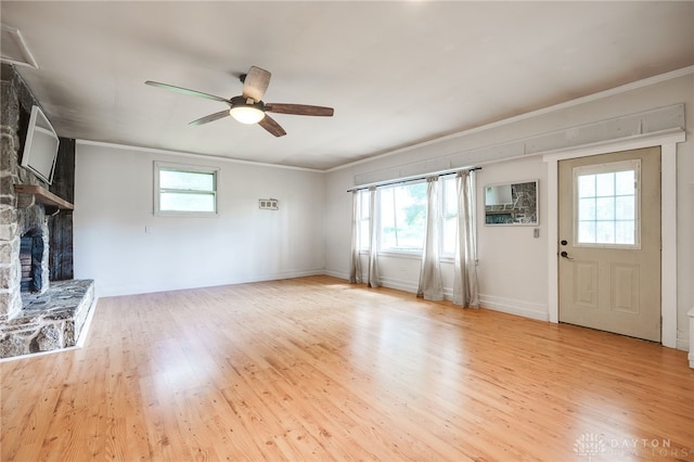 3201 Sears Rd, Spring Valley Twp, OH 45370 - unfurnished living room featuring a stone fireplace, ornamental molding, a ceiling fan, and light wood-type flooring