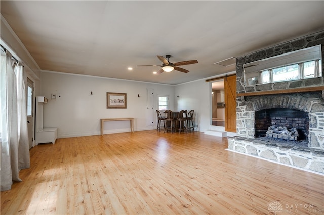 3201 Sears Rd, Spring Valley Twp, OH 45370 - living room featuring a ceiling fan, wood finished floors, crown molding, a fireplace, and a barn door