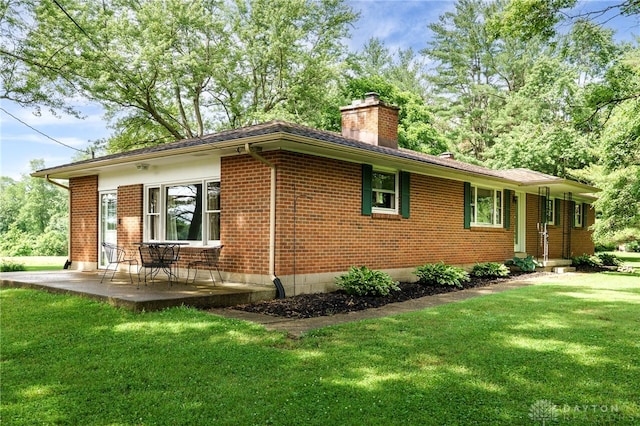 3201 Sears Rd, Spring Valley Twp, OH 45370 - view of home's exterior with a chimney, brick siding, a lawn, and a patio area