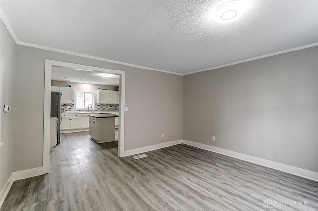 1601 Rausch Ave, Dayton, OH 45432 - unfurnished living room featuring light wood finished floors, ornamental molding, and a textured ceiling