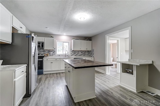 1601 Rausch Ave, Dayton, OH 45432 - kitchen with wood counters, stainless steel appliances, light wood-style flooring, decorative backsplash, and a textured ceiling