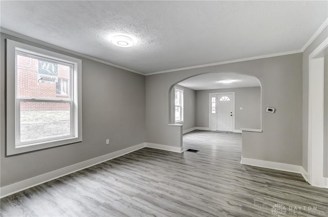 1601 Rausch Ave, Dayton, OH 45432 - spare room featuring arched walkways, wood finished floors, ornamental molding, healthy amount of natural light, and a textured ceiling