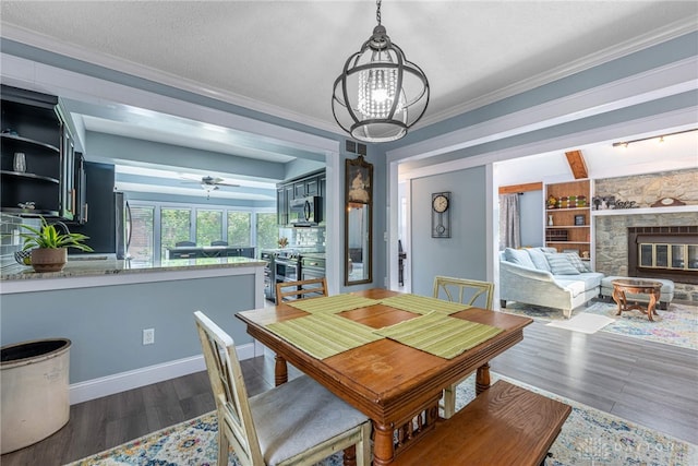 195 Sycamore Creek Dr, Springboro, OH 45066 - dining area with wood finished floors, a stone fireplace, a ceiling fan, crown molding, and a chandelier