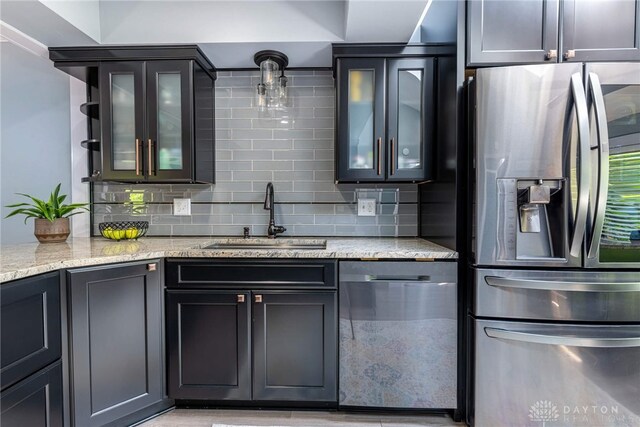 195 Sycamore Creek Dr, Springboro, OH 45066 - kitchen with appliances with stainless steel finishes, backsplash, light stone countertops, and glass insert cabinets