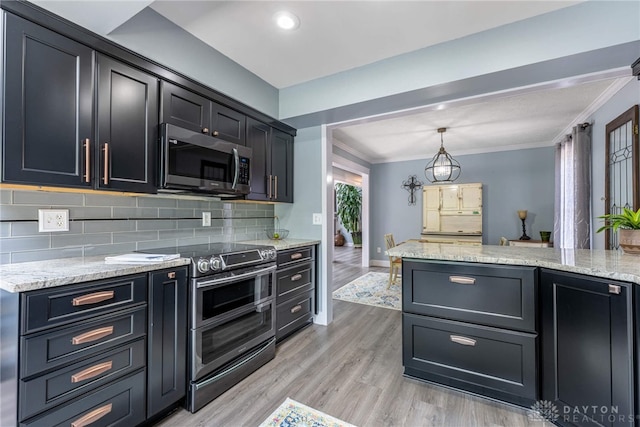 195 Sycamore Creek Dr, Springboro, OH 45066 - kitchen with appliances with stainless steel finishes, tasteful backsplash, light wood finished floors, light stone counters, and dark cabinetry