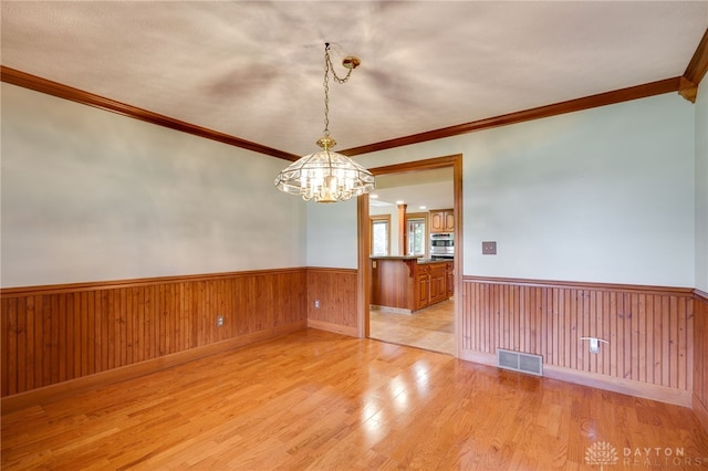 4911 Arabian Dr, Fairborn, OH 45324 - empty room with a wainscoted wall, light wood-type flooring, a chandelier, ornamental molding, and wooden walls