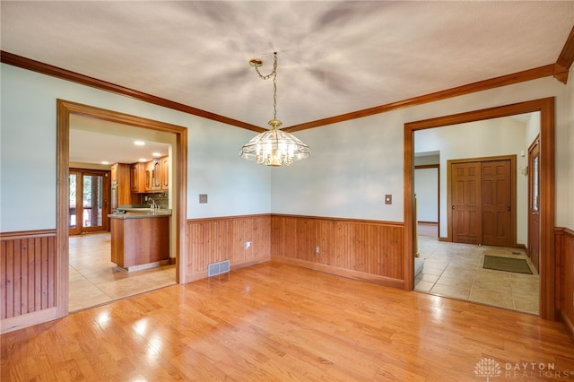 4911 Arabian Dr, Fairborn, OH 45324 - unfurnished room featuring light wood-style floors, a wainscoted wall, a chandelier, crown molding, and wooden walls