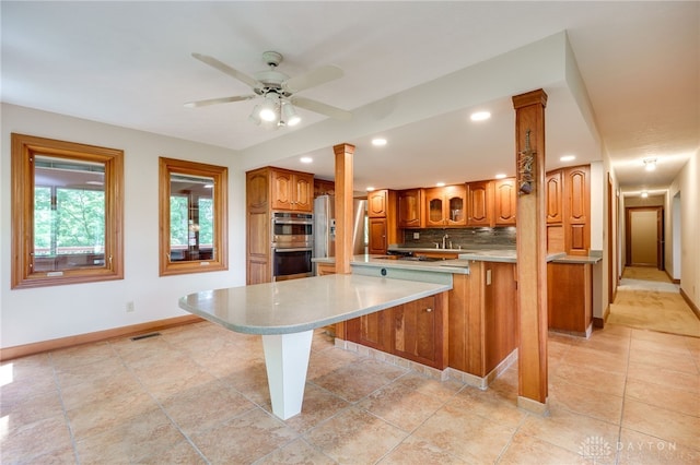 4911 Arabian Dr, Fairborn, OH 45324 - kitchen featuring ornate columns, appliances with stainless steel finishes, brown cabinets, decorative backsplash, and ceiling fan