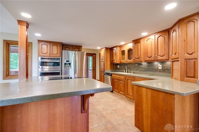 4911 Arabian Dr, Fairborn, OH 45324 - kitchen featuring appliances with stainless steel finishes, a peninsula, tasteful backsplash, brown cabinetry, and recessed lighting
