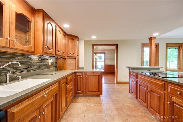 4911 Arabian Dr, Fairborn, OH 45324 - kitchen with black electric stovetop, backsplash, brown cabinetry, glass insert cabinets, and recessed lighting